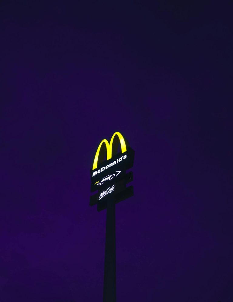 A glowing McDonald's sign stands out against a deep purple night sky.