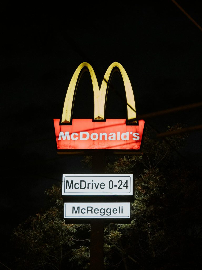 Bright McDonald's signage glowing at night, displaying McDrive 0-24 and McReggeli in Hungary.